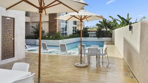 un patio con mesa, sillas y sombrillas en Bocobay Aracari Condo Hotel, en Palm-Eagle Beach