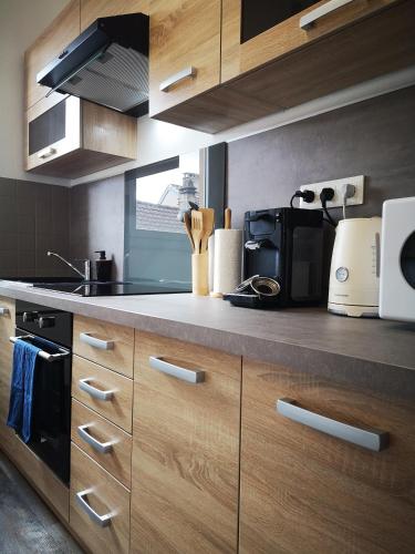a kitchen with wooden cabinets and a stove top oven at Le petit cocon de la poste in Gourdon-en-quercy