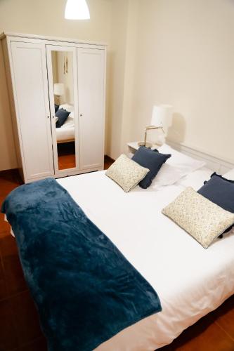 a large white bed with blue pillows in a bedroom at Apartamentos Costa Norte in San Vicente de la Barquera