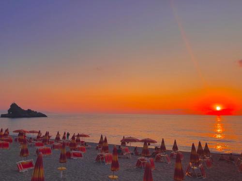a beach with chairs and umbrellas at sunset at La Tonnara B&B in Palmi