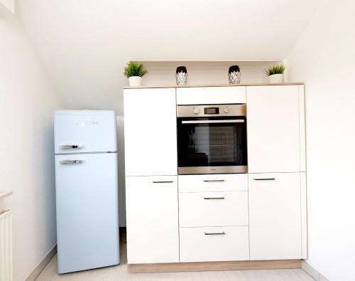 a kitchen with white cabinets and a refrigerator at 2,5-Zimmer inkl Arbeitsplatz, WLAN & free Netflix, Amazon-Free Parken vollausgestattete Wohnung, 24h Check In in Hamm