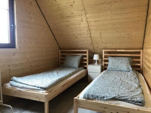 2 łóżka w pokoju z drewnianymi ścianami w obiekcie Hippalos Domki Lux w mieście Jarosławiec