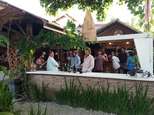 a group of people standing at a bar at Mentawai Bagus Local Homestay in Tua Pejat