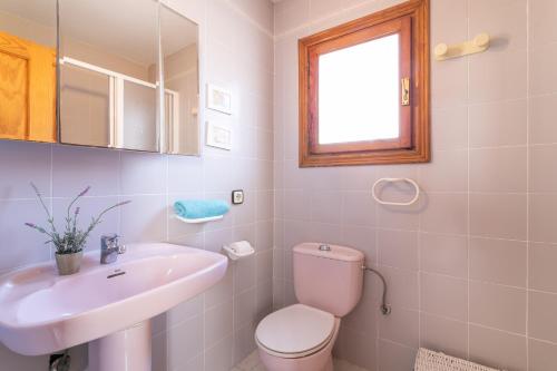 Un baño blanco con inodoro y lavabo. en Casa en la playa con piscinas E, en Puerto Marino