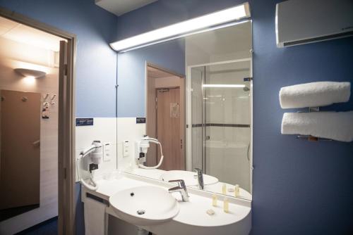 a bathroom with a sink and a mirror at ACE Hôtel Metz in Metz