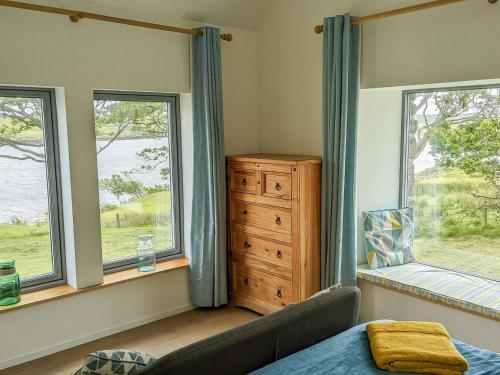 a bedroom with two windows and a dresser and a bed at The Beach House in Dunvegan