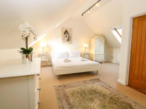 ein Schlafzimmer mit einem weißen Bett im Dachgeschoss in der Unterkunft The Old Cartshed in Lowestoft