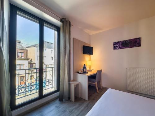 カンペールにあるHotel De La Gareのベッド、デスク、窓が備わるホテルルームです。