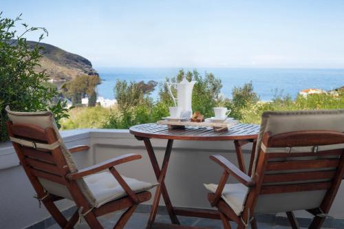 una mesa y 2 sillas en un balcón con vistas al océano en Alpha House Gialia en Ándros