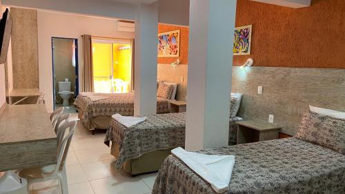 a hotel room with three beds and a table at Kaliman Pousada in Ubatuba