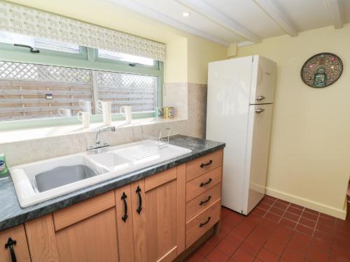 a kitchen with a sink and a refrigerator at Church Hill Cottage in Tavistock