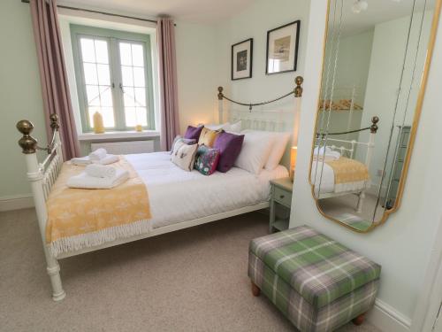 Schlafzimmer mit einem weißen Bett und einem Spiegel in der Unterkunft Church Hill Cottage in Tavistock