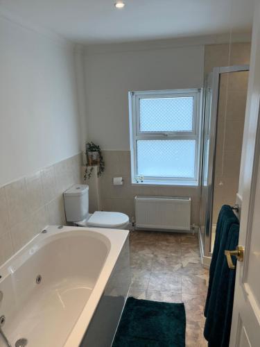 a bathroom with a tub and a toilet and a window at The Apartment, Bridge House in Laxey