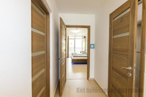 a corridor with wooden doors in a house at Tisza Gyöngye Apartmanok in Szeged