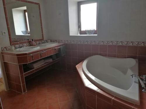 La salle de bains est pourvue d'une baignoire, d'un lavabo et d'un miroir. dans l'établissement Gites le mas clémentine Le Coquelicot, à Saint-Julien-du-Serre