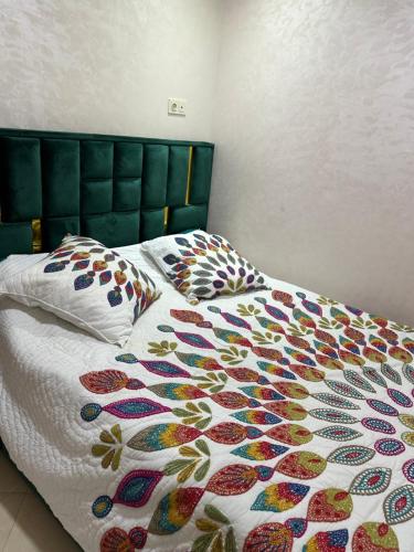 Una cama con una manta colorida y almohadas. en Lmasala, en Meknès