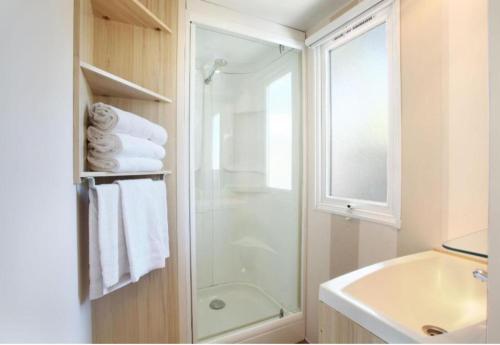 a white bathroom with a shower and a sink at Bungalow dans une résidence en plein air a l'Elysée vagues océanes "capfun" in Le Grau-du-Roi