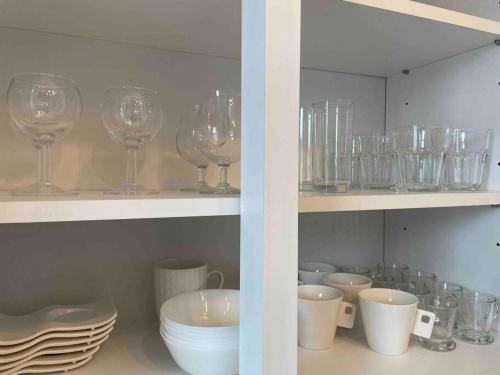 a shelf filled with wine glasses and bowls and plates at Agréable duplex proche de toutes commodités in Ans