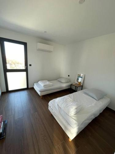 Cette chambre blanche dispose de deux lits et d'une fenêtre. dans l'établissement Villa détente à 150 m de l'océan - Bisca Plage, à Biscarrosse