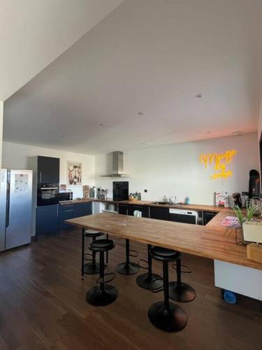 une grande cuisine avec une table et des tabourets en bois dans l'établissement Villa détente à 150 m de l'océan - Bisca Plage, à Biscarrosse