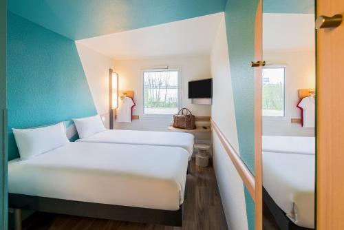 um quarto de hotel com duas camas e uma janela em Ibis budget Regensburg Ost em Regensburg