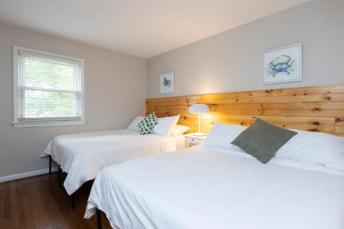 Duas camas num quarto com lençóis brancos e uma janela. em Natural Beauty B em Virginia Beach