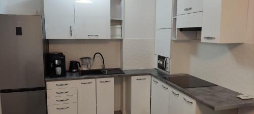 una cocina con armarios blancos y fregadero en Apartament Świdnica, en Świdnica