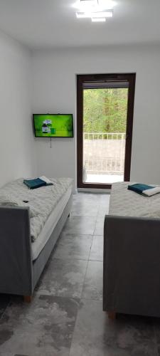 two beds in a room with a large window at Apartament Świdnica in Świdnica