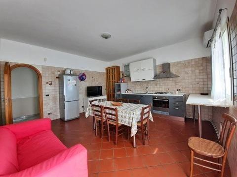 a kitchen with a red couch and a table with chairs at Etnadia in Santa Maria di Licodia