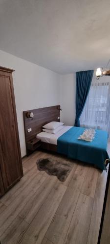 1 dormitorio con 1 cama y suelo de madera en Popasul Moților, en Răchiţele