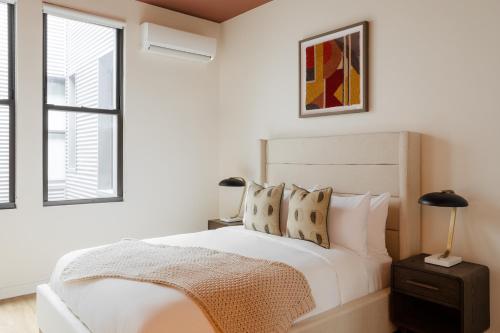 ein weißes Schlafzimmer mit einem Bett und zwei Fenstern in der Unterkunft Found Chicago powered by Sonder in Chicago
