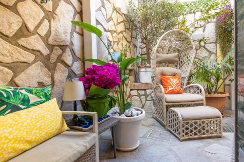 a patio with wicker chairs and flowers and plants at Suite Apartment Capri con Jacuzzi in Piazzetta in Capri