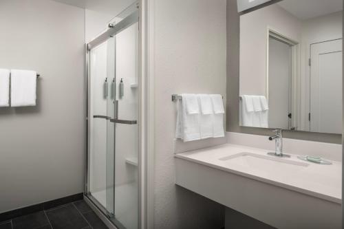 La salle de bains blanche est pourvue d'un lavabo et d'une douche. dans l'établissement Courtyard by Marriott Dayton Beavercreek, à Beavercreek