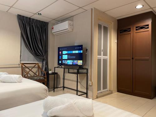 a hotel room with a bed and a flat screen tv at Barrack Street Hotel in Taiping
