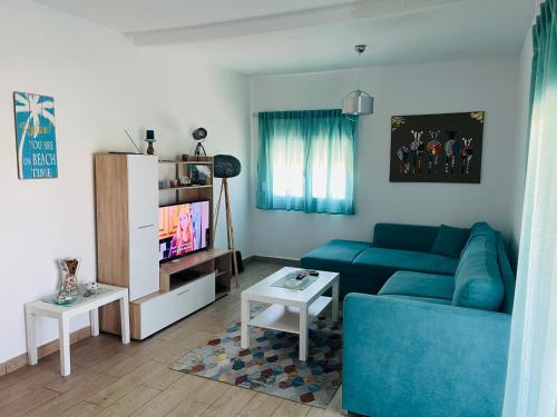 een woonkamer met een blauwe bank en een tafel bij Villa ,,Sea Breeze,, - home by the sea in Néa Ankhíalos