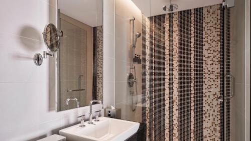 a white bathroom with a sink and a shower at Costa Executive Residences in Nha Trang