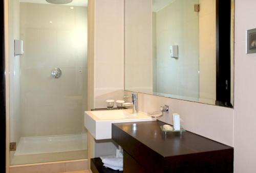 a bathroom with a sink and a mirror and a shower at AP Adriana Beach Resort in Albufeira