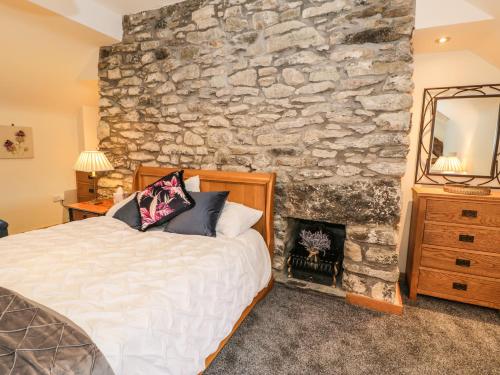 een slaapkamer met een stenen muur, een bed en een open haard bij Hen Dy Craig Yr Ronwy in Bala