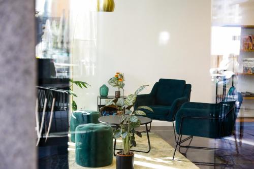 a room with two blue chairs and a table with a plant at Boutique Hotel Piazza Grande in Locarno