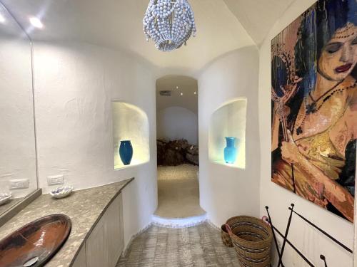 a bathroom with a sink and a painting on the wall at San Teodoro Punta Est Magnifico Trilocale Vista Mare in Capo Coda Cavallo