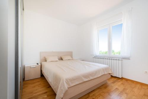 ein weißes Schlafzimmer mit einem Bett und einem Fenster in der Unterkunft Ferienhaus Dalmatia bei Zadar in Zadar