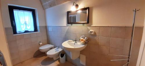 ein Badezimmer mit einem Waschbecken, einem WC und einem Spiegel in der Unterkunft Lamia Pieranna in Cisternino