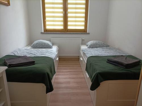 a room with two beds with green sheets and a window at Apartament Green Hill in Szklarska Poręba