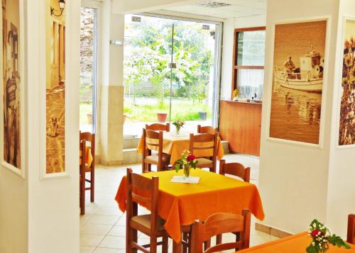 a restaurant with tables and chairs and a window at Hotel TRIADA in Limenaria