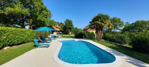 une piscine avec des chaises et un parasol dans l'établissement Combe Belle, à Vézac