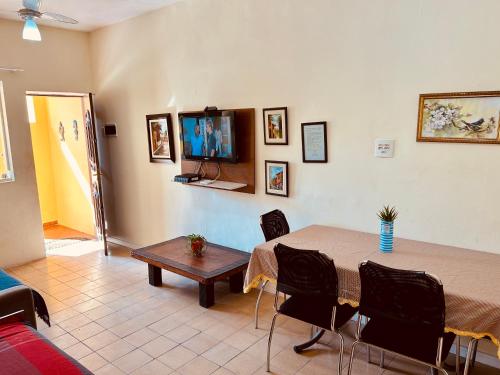 a living room with a table and a television at Casa Amarela in Praia Grande
