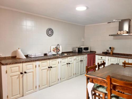a kitchen with white cabinets and a table in it at La casita de la abuela in Villarcayo