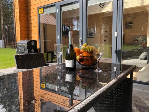a glass table with a bowl of fruit and a bottle of wine at Grzybowska Osada in Grzybowo