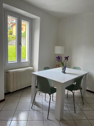 a white table with chairs and a vase of flowers on it at Casa Dilma in Lenno