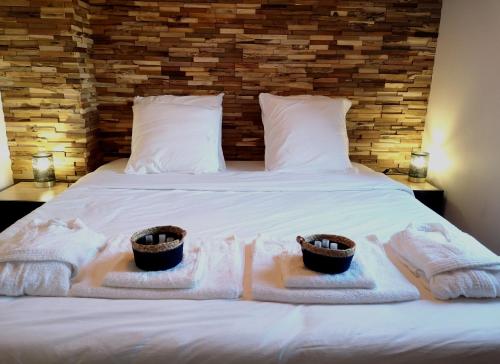 Una cama con toallas y dos cestas. en Elo Spa, en Saint-Quentin